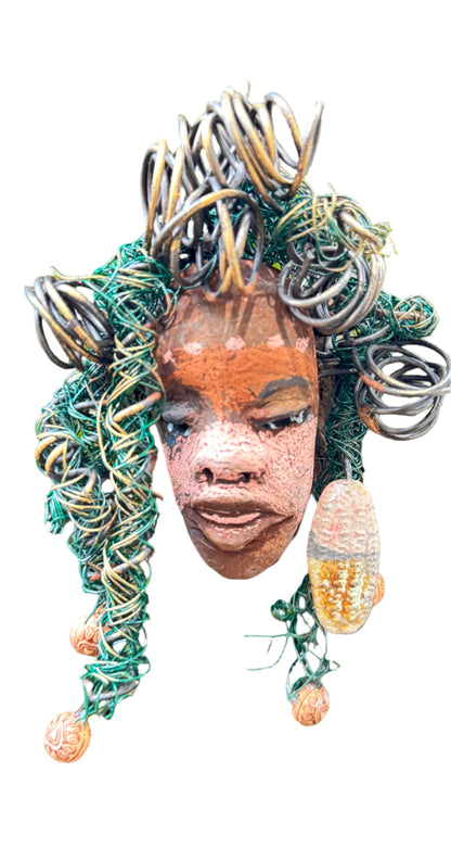Davina is a 4” x 5” 5oz. mixed media raku fire mask made with 20 feet of 24 and 16 gauge wire. It boasts a striking, three-colored design and includes a large Raku fired earring with wooden beads. This unique piece is the perfect addition to your HerDew mask collection. Experience the enhanced beauty of Davina when paired with tree bark.