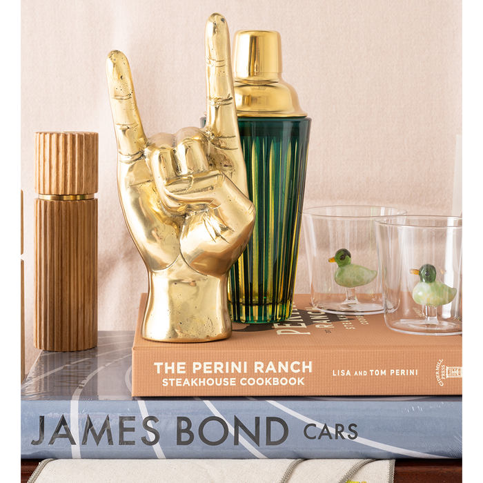 Decorative items including a gold hand-shaped object, cocktail shaker, and books on a surface.