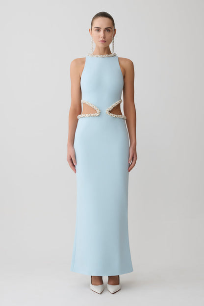 Woman wearing a light blue evening gown with lace details on a white background