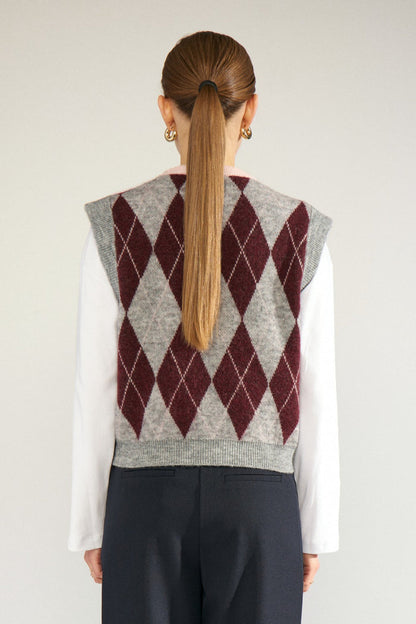 Shop the Nümph NUTIKLA Vest in Medium Grey Melange at Dotique. A wool blend argyle knitted vest in grey and burgundy with a contrasting pink neckline.