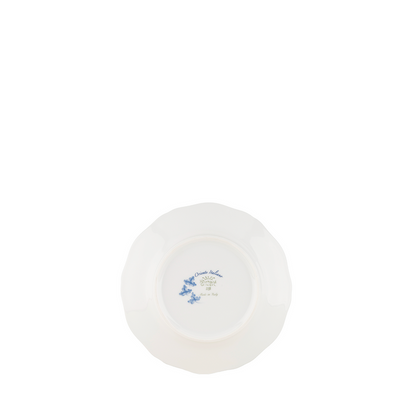 White ceramic bread and butter plate with scalloped edges and delicate blue floral design at center.