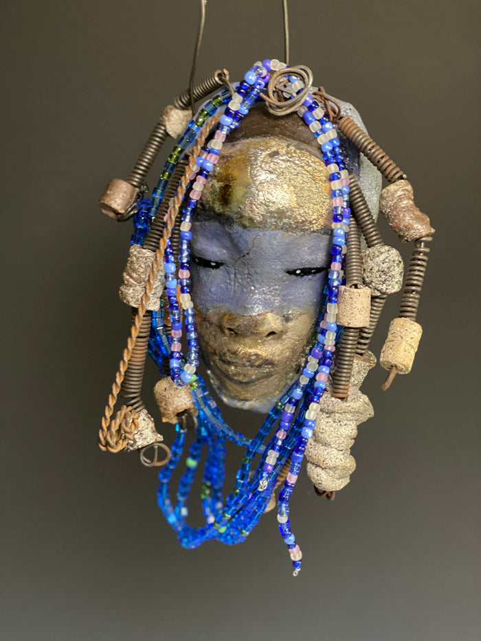Meet Randi! I started making art soon after seeing authentic African artwork at the Smithsonian Museum of African Art. I was in total awe. Randi was inspired by my visit there.   Randi has a two tone complexion of golden silver and blue. She is 8" x 6" and weighs 14 ozs. Randi has over 10 raku beads. She has over 200 of multi shade of blue and white mini beads. Randi has over 10 feet of  coiled copper and 16 gauge wire hair.