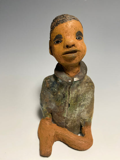 Ray is one happy studious teen who will lighten up a room!  Ray stands 7" x 3" x 3.5" and weighs 15 ozs. He has a metallic  green jacket with pull up collar . Ray complexion is honey brown. He has no facial hair and wears a bright smile. His arms are folded as he prepares to be invited into your home!