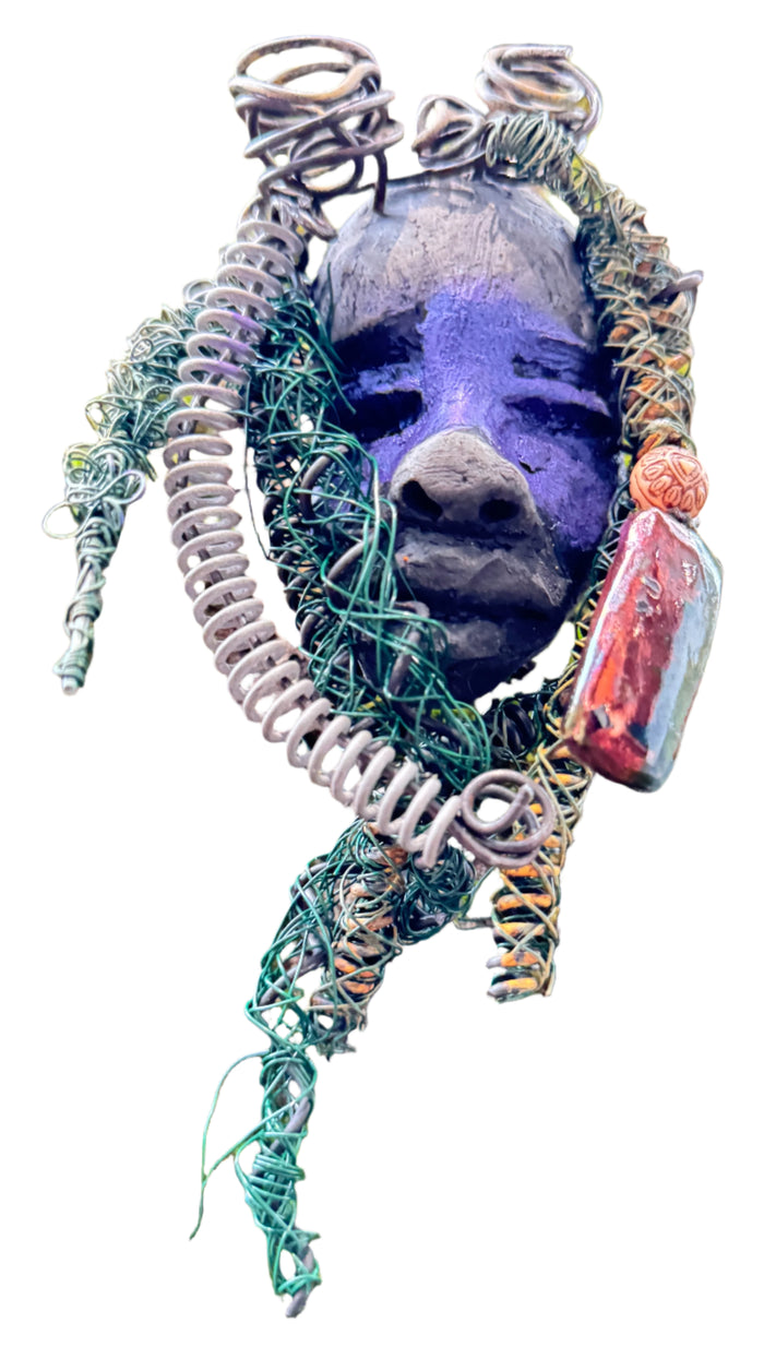 Rayda is a 4” x 6” 5oz. mixed media raku fire mask that includes 15 feet of 24 and 16 gauge wire. It has a Smokey black two tone complexion and a large metallic Raku fired earring with a wooden bead. Its earthy appeal is enhanced when displayed with natural tree bark, making it a lovely addition to your HerDew mask collection.