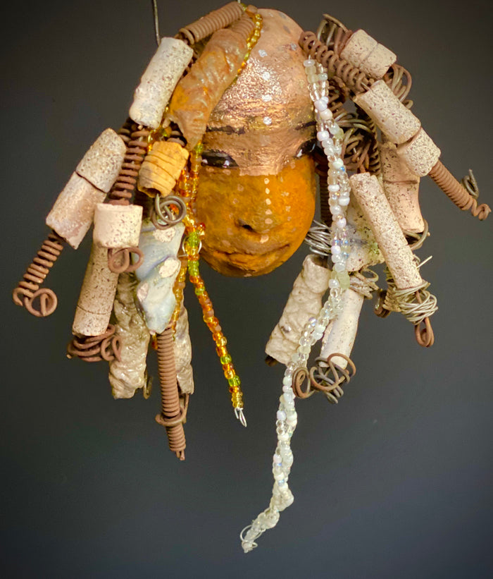 I started making art soon after seeing authentic African artwork at the Smithsonian Museum of African Art. I was in total awe.  Ryanna was inspired by my visit there.  Ryanna  is 8”x 6” and weighs 13 ozs. She has a two tone earthy honey and metallic gold complexion. Ryanna has  over 20 raku beads and over a 100 mini colored and white beads  spiral coils of hair. She more than 10 feet of 16 gauge wire hair