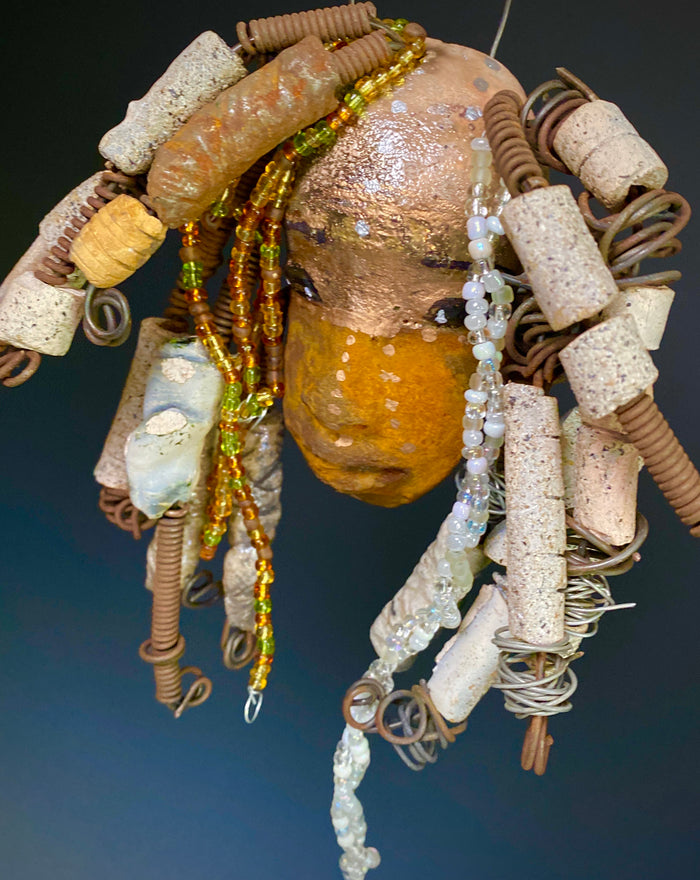 I started making art soon after seeing authentic African artwork at the Smithsonian Museum of African Art. I was in total awe.  Ryanna was inspired by my visit there.  Ryanna  is 8”x 6” and weighs 13 ozs. She has a two tone earthy honey and metallic gold complexion. Ryanna has  over 20 raku beads and over a 100 mini colored and white beads  spiral coils of hair. She more than 10 feet of 16 gauge wire hair