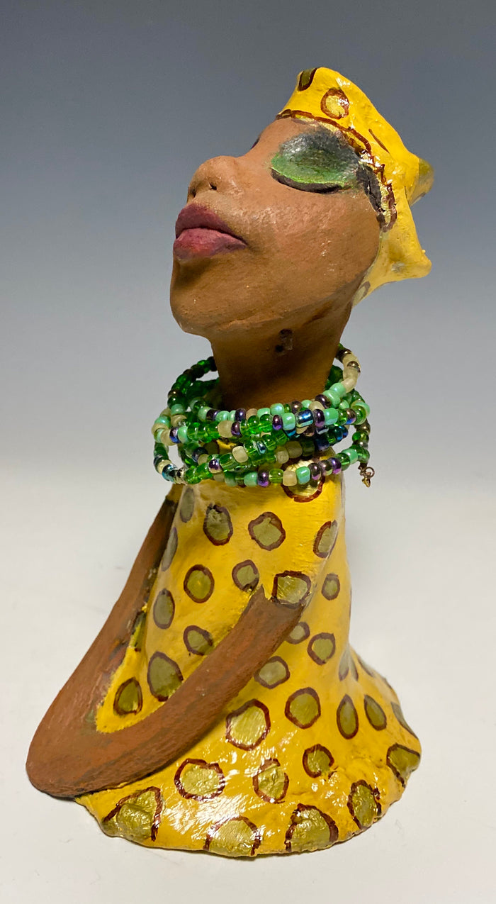 Meet Sharon! Sharon stands" 8 x 5" x 5" and weighs 1.5 lbs She wears a cute spotted autumn yellow dress with matching hat and emerald green beads. Her long loving arms rest at her side. Check out Sharon's little sister named Shelia! With the current situation we All are going through, Shelia will place a smile on your face during this challenging time.