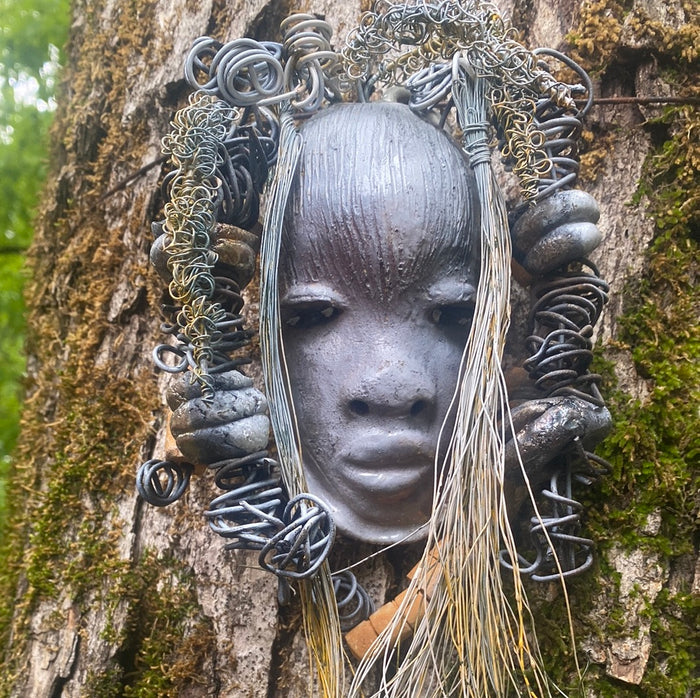 Zaya has a metallic  white complexion. She is 7" x 8" and weighs  11 ozs. Zaya has over 15 handmade raku fired beads. Zaya has over 25 feet of  copper coiled 16 gauge wire hair