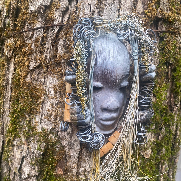 Zaya has a metallic  white complexion. She is 7" x 8" and weighs  11 ozs. Zaya has over 15 handmade raku fired beads. Zaya has over 25 feet of  copper coiled 16 gauge wire hair