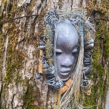 Zaya has a metallic  white complexion. She is 7" x 8" and weighs  11 ozs. Zaya has over 15 handmade raku fired beads. Zaya has over 25 feet of  copper coiled 16 gauge wire hair