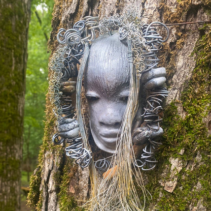 Zaya has a metallic  white complexion. She is 7" x 8" and weighs  11 ozs. Zaya has over 15 handmade raku fired beads. Zaya has over 25 feet of  copper coiled 16 gauge wire hair